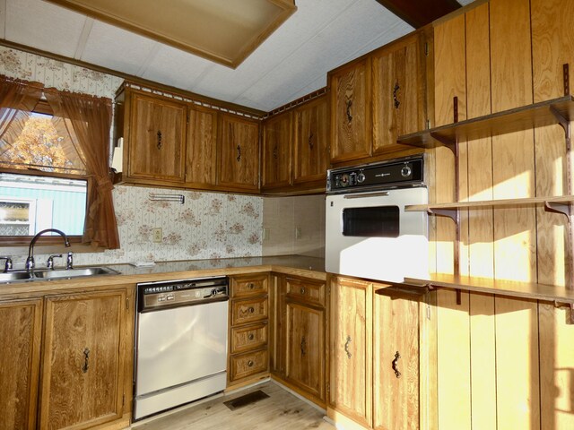 3924 W Jefferson Ave Unit 3924, Trenton, MI 48183 - kitchen featuring dishwasher, oven, a sink, wallpapered walls, and brown cabinetry