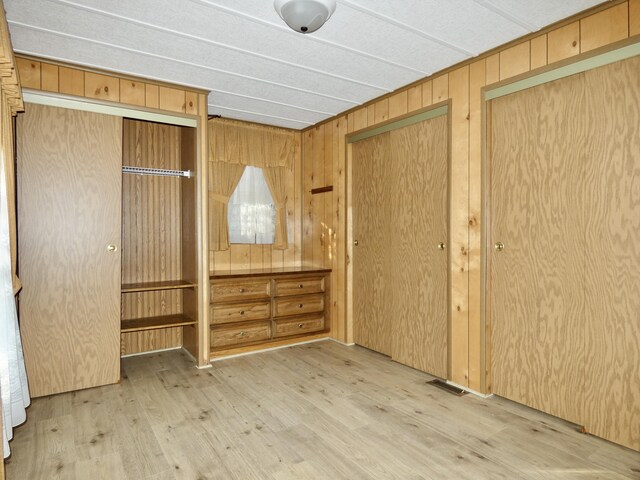 3924 W Jefferson Ave Unit 3924, Trenton, MI 48183 - unfurnished bedroom with wood finished floors, wood walls, and two closets