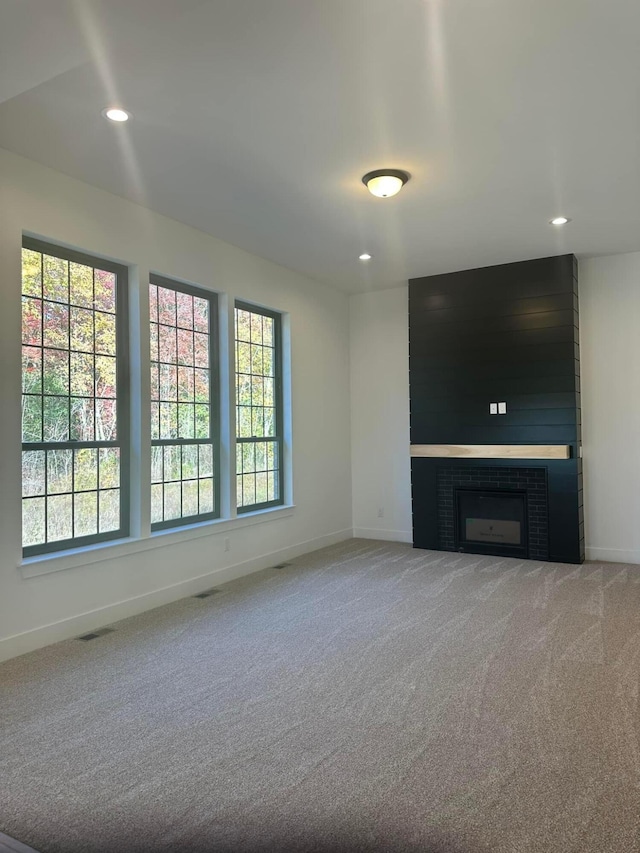 unfurnished living room with carpet and a brick fireplace