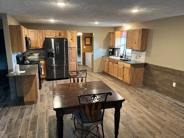 kitchen featuring hardwood / wood-style flooring, sink, a textured ceiling, and black appliances