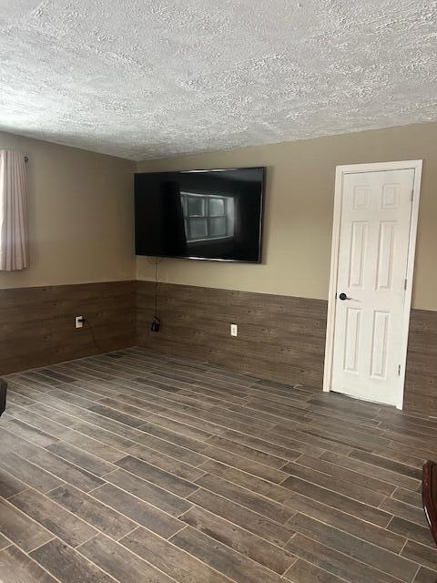 unfurnished room with dark wood-type flooring, a textured ceiling, and wooden walls