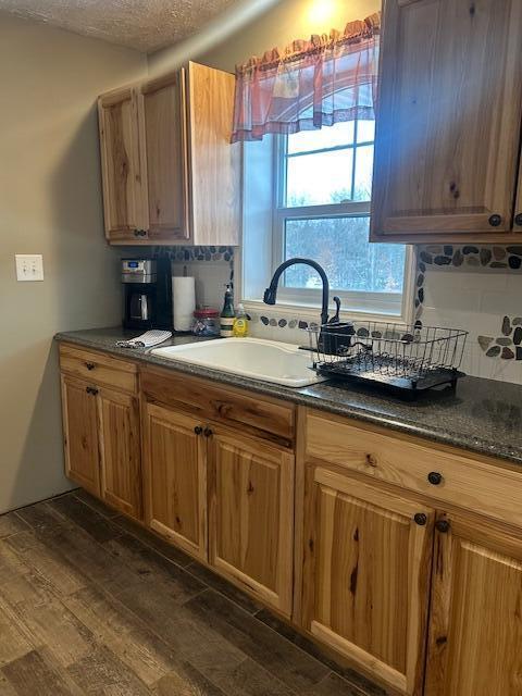 kitchen featuring tasteful backsplash, dark hardwood / wood-style flooring, sink, and a textured ceiling