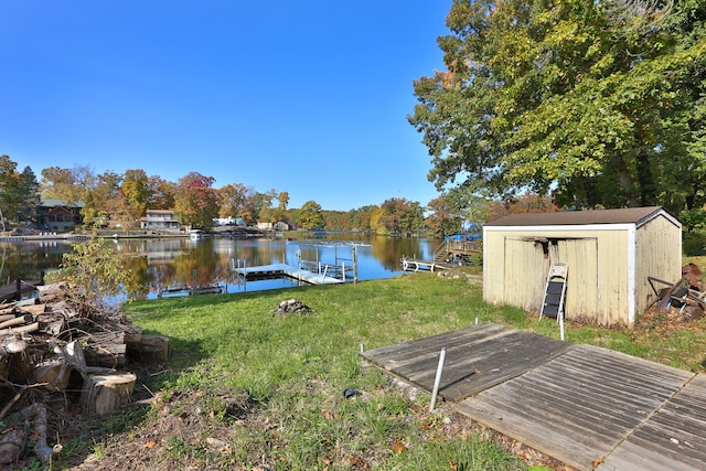 view of yard featuring a water view, a dock, and a storage shed