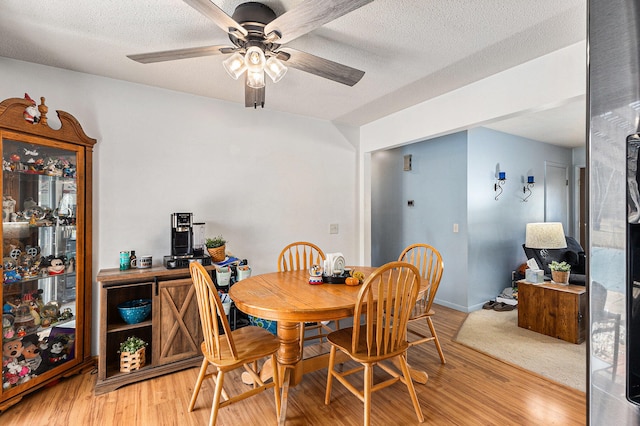 dining space with ceiling fan, a textured ceiling, and light wood-type flooring