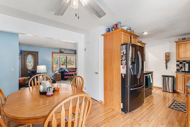 dining room featuring ceiling fan, light wood-type flooring, and a textured ceiling