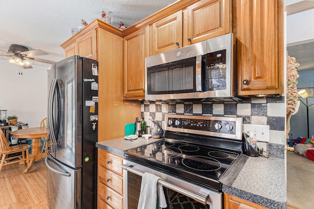 kitchen featuring backsplash, ceiling fan, light wood-type flooring, a textured ceiling, and stainless steel appliances