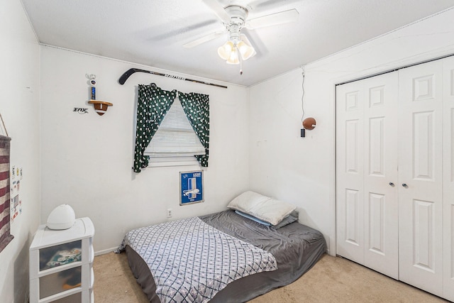 carpeted bedroom with ceiling fan and a closet