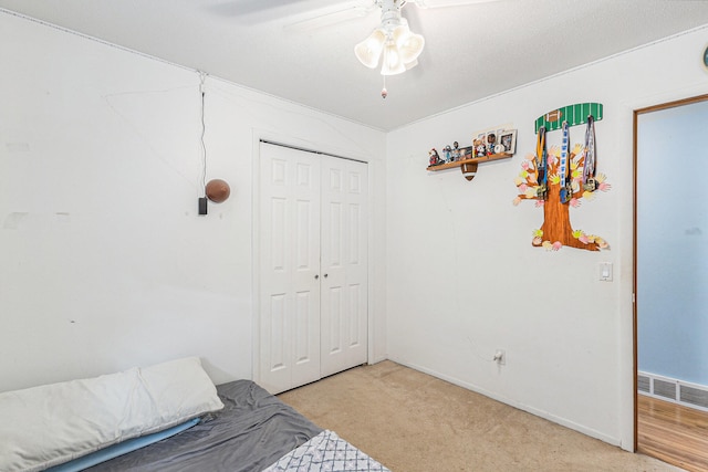 carpeted bedroom with ceiling fan and a closet