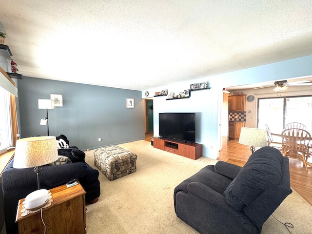 living room featuring ceiling fan, a textured ceiling, and light colored carpet