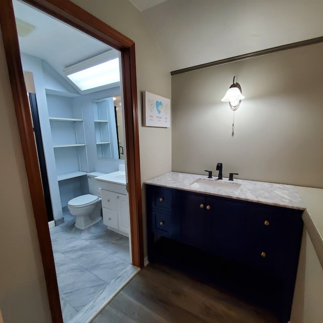 bathroom with hardwood / wood-style flooring, toilet, lofted ceiling, and vanity