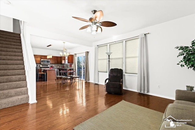 living room featuring ceiling fan with notable chandelier and dark hardwood / wood-style flooring