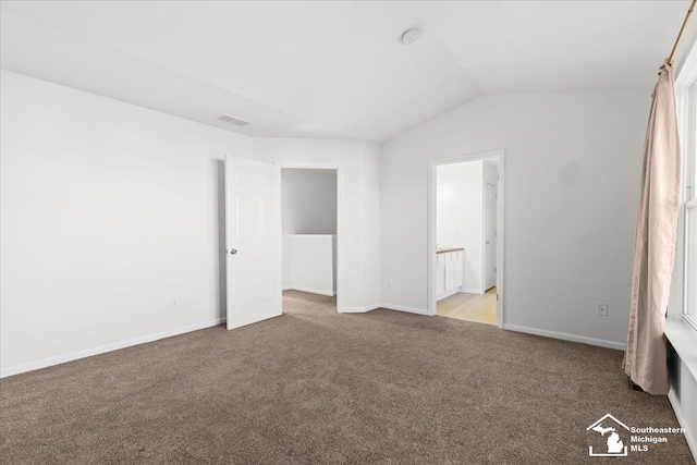 unfurnished bedroom with ensuite bathroom, light colored carpet, and vaulted ceiling