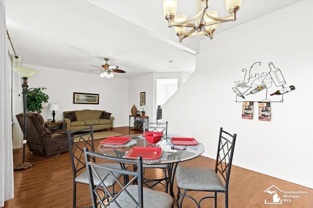 dining room with ceiling fan with notable chandelier and wood-type flooring