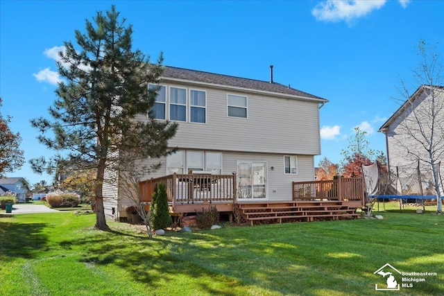 rear view of house featuring a lawn, a deck, and a trampoline