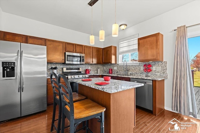 kitchen featuring decorative backsplash, appliances with stainless steel finishes, dark hardwood / wood-style flooring, sink, and a kitchen island