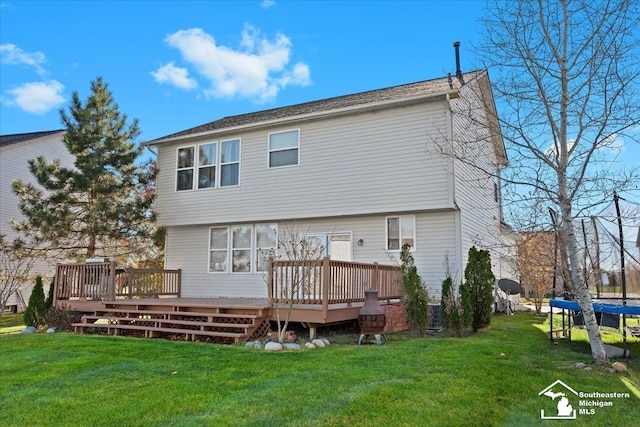 back of property with a lawn, a trampoline, and a wooden deck