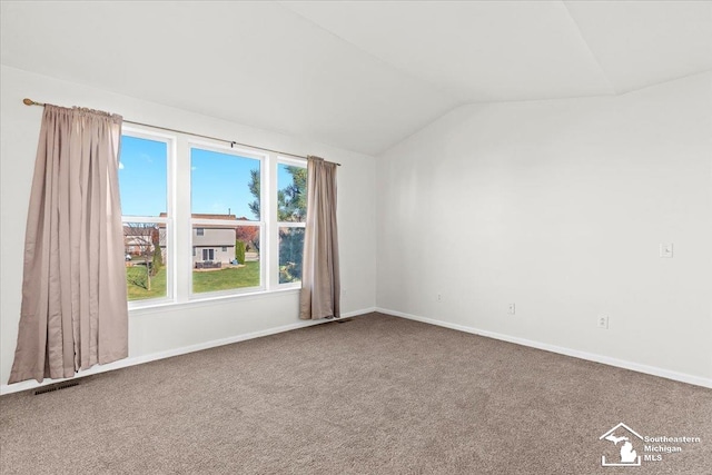 carpeted spare room with vaulted ceiling