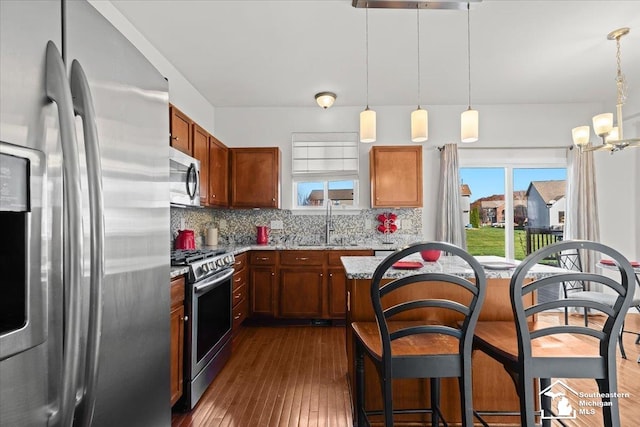 kitchen featuring decorative light fixtures, backsplash, stainless steel appliances, and dark wood-type flooring