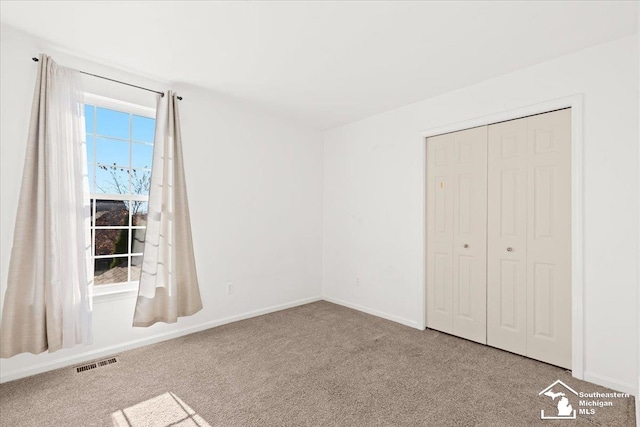 unfurnished bedroom featuring light carpet and a closet