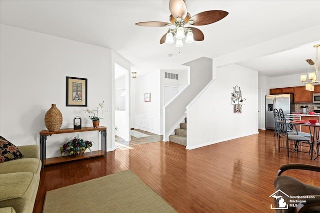 living room featuring wood-type flooring and ceiling fan with notable chandelier