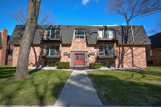 view of front of house featuring a balcony, french doors, and a front yard