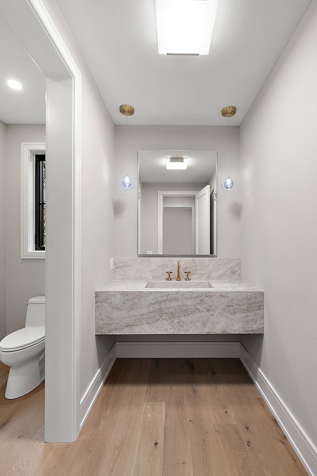 bathroom with toilet, hardwood / wood-style floors, and sink