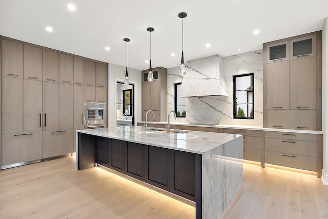 kitchen featuring a spacious island, hanging light fixtures, light hardwood / wood-style flooring, decorative backsplash, and light stone counters