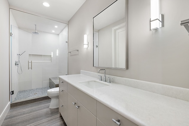 bathroom with hardwood / wood-style flooring, vanity, toilet, and walk in shower