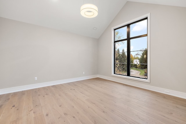 spare room featuring light wood-type flooring and vaulted ceiling