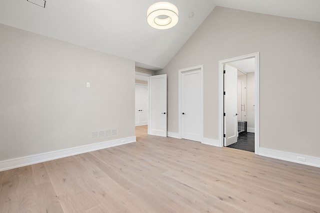 unfurnished bedroom featuring high vaulted ceiling and light hardwood / wood-style floors