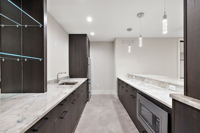 kitchen with light stone counters, sink, decorative light fixtures, and appliances with stainless steel finishes