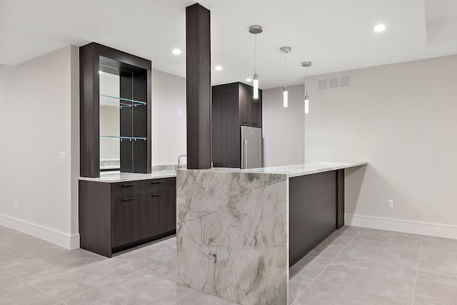 bar featuring decorative light fixtures, light stone countertops, and dark brown cabinetry