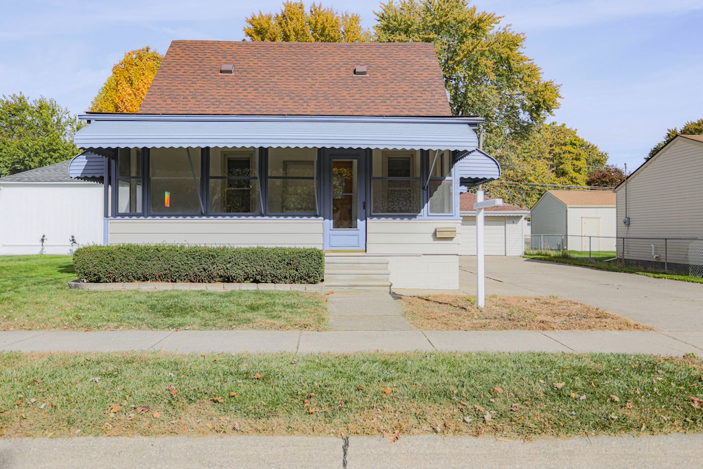 bungalow with an outbuilding, a garage, and a front lawn