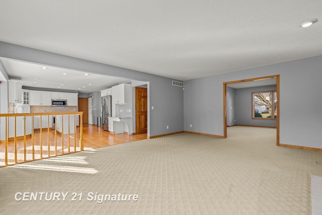 unfurnished living room featuring sink and light colored carpet