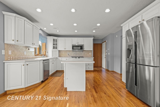 kitchen featuring a center island, white cabinetry, appliances with stainless steel finishes, and light hardwood / wood-style flooring