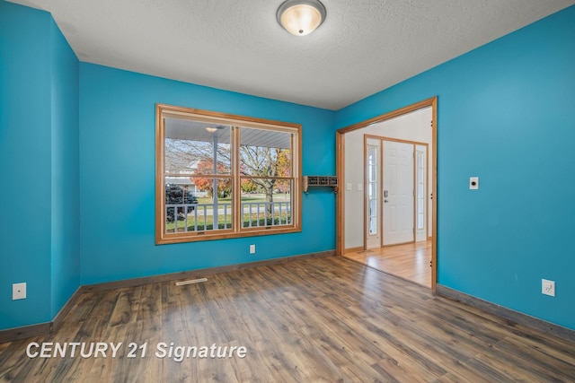 empty room featuring a textured ceiling and dark hardwood / wood-style floors