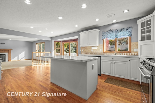 kitchen with white cabinetry, sink, stainless steel appliances, light hardwood / wood-style flooring, and a kitchen island