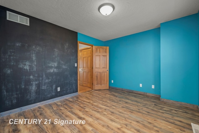 unfurnished bedroom featuring lofted ceiling, hardwood / wood-style floors, and a textured ceiling