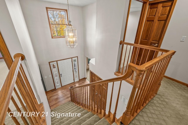 stairway featuring wood-type flooring and an inviting chandelier