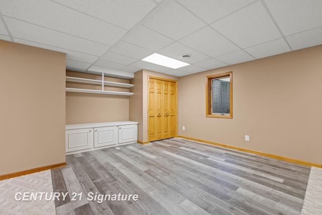 interior space with a drop ceiling and light wood-type flooring