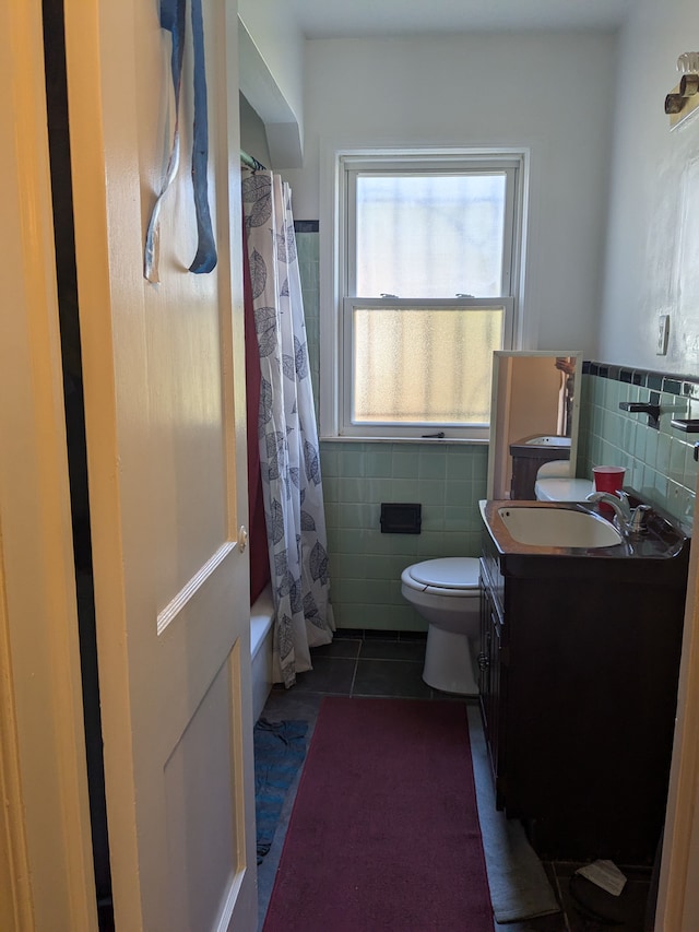 full bathroom with tile patterned floors, vanity, shower / bath combo with shower curtain, tile walls, and toilet