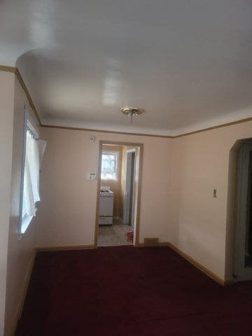 empty room featuring ornamental molding and washer / dryer