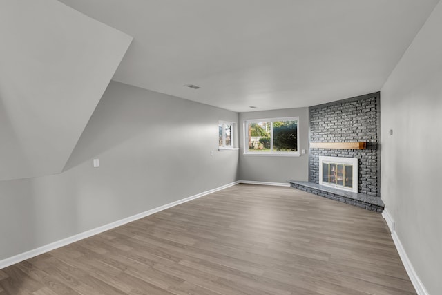 unfurnished living room featuring a brick fireplace and light hardwood / wood-style flooring