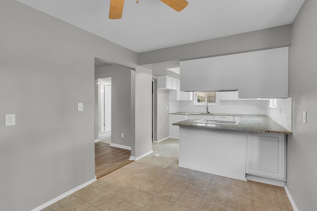 kitchen featuring sink, kitchen peninsula, white cooktop, light stone counters, and white cabinetry