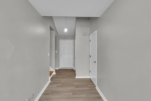 hall with lofted ceiling and light wood-type flooring