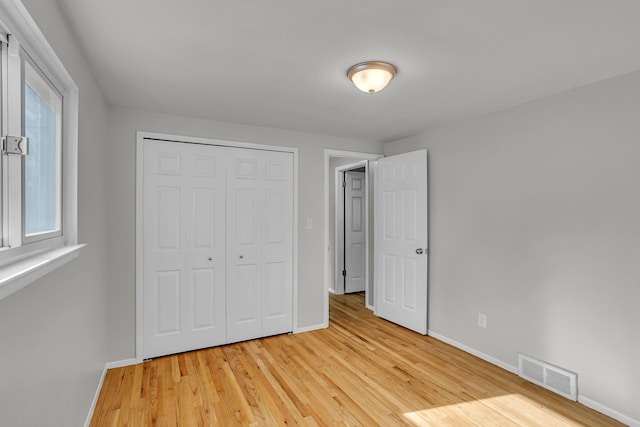 unfurnished bedroom with a closet and light wood-type flooring