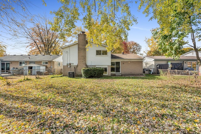 back of property with a yard and central AC