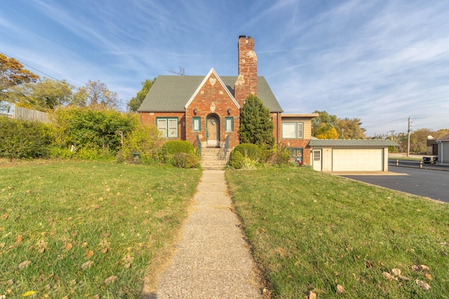 english style home with an outbuilding, a garage, and a front lawn