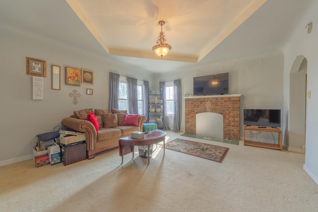 living room with a raised ceiling, carpet floors, and a fireplace