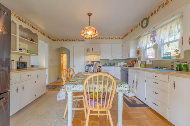 kitchen with white cabinets, decorative light fixtures, stainless steel refrigerator, and sink